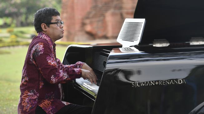 Pianis dan komponis Ananda Sukarlan memainkan piano Sjuman+Renanda yang mendapat rekor MURI untuk 'grand piano pertama buatan Indonesia' pada rangkaian konser Raspodia Nusantara dan Kejayaan Nusantara di Candi Gapura Bajang Ratu, Trowulan, Mojokerto, Jawa Timur, Sabtu (3/10/2020). [ANTARA FOTO/Zabur Karuru]