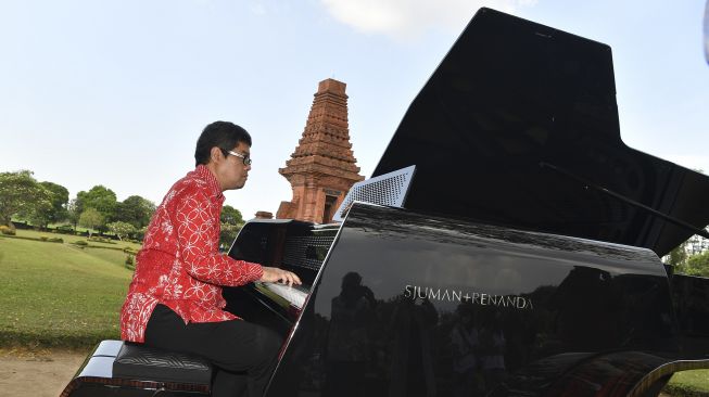 Pianis dan komponis Ananda Sukarlan memainkan piano Sjuman+Renanda yang mendapat rekor MURI untuk 'grand piano pertama buatan Indonesia' pada rangkaian konser Raspodia Nusantara dan Kejayaan Nusantara di Candi Gapura Bajang Ratu, Trowulan, Mojokerto, Jawa Timur, Sabtu (3/10/2020). [ANTARA FOTO/Zabur Karuru]