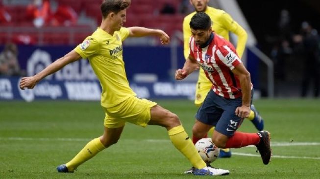 Pemain Atletico Madrid Luis Suarez berjibaku dengan pemain Villarreal dalam pertandingan La Liga di Estadio Wanda Metropolitano, Sabtu (3/10/2020). [AFP]