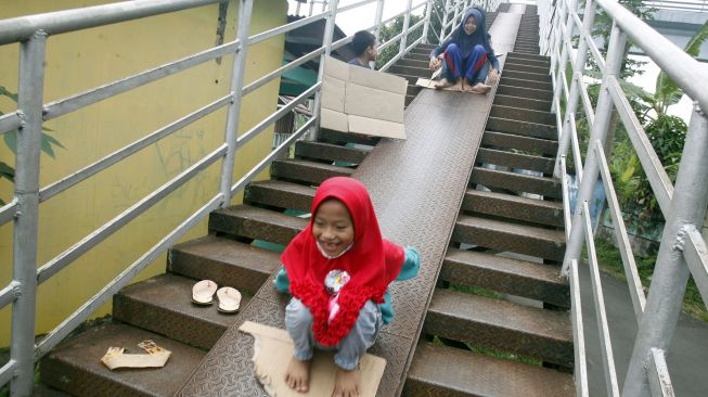 Sejumlah anak bermain perosotan di jembatan penyebrangan tol di Ciawi, Kabupaten Bogor, Jawa Barat, Sabtu (3/10/2020). [ANTARA FOTO/Yulius Satria Wijaya]