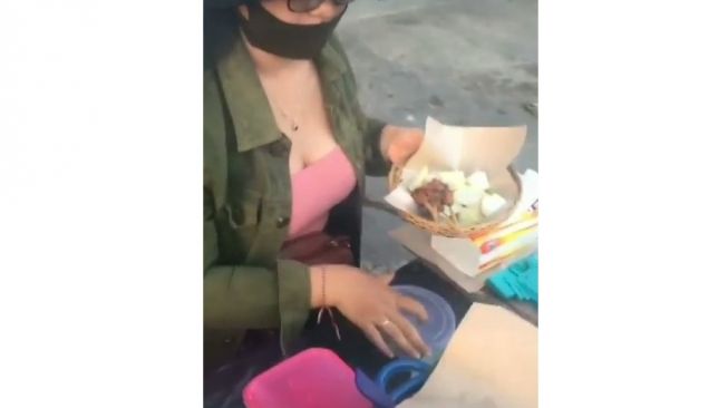 Perempuan semok mengenakan baju pink jual sate babi di pinggir jalan di Bali. (@denpasarnow)