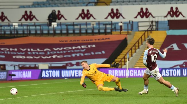 Gelandang Aston Villa Jack Grealish (tengah) mencetak gol ketujuh mereka usai melewati kiper Liverpool Adrian selama pertandingan sepak bola Liga Premier Inggris antara Aston Villa melawan Liverpool di Villa Park, Birmingham, Inggris, Senin (5/10) dini hari WIB. [Catherine Ivill / POOL / AFP]