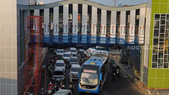 Kendaraan melintas dibawah jembatan penghubung halte Transjakarta Pasar Senen yang sedang dibangun di Kawasan Senen, Jakarta Pusat, Senin (5/10). [Suara.com/Alfian Winanto]