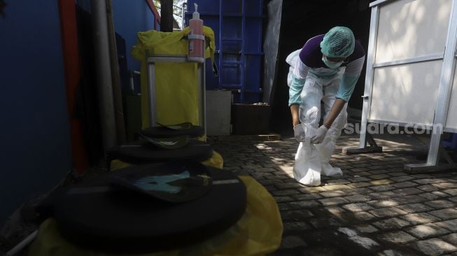 Petugas medis melepas baju hazmat sebelum membersihkan diri (dekontaminasi) usia bertugas menangani pasien COVID-19 di Puskesmas Kecamatan Gambir, Jakarta, Selasa (6/10/2020). [Suara.com/Angga Budhiyanto]