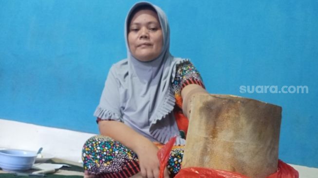 Ketua RT, Indah Safitri memperlihatkan benda dari ledakan tabung nitrogen di Pontianak yang melambung jauh ke rumah warga.(Suara.com/Eko Susanto)