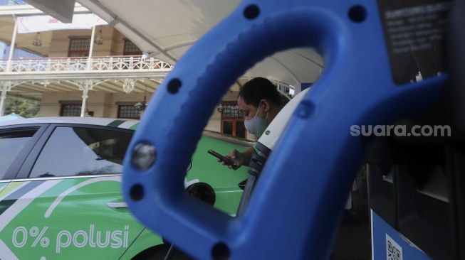 Pengemudi taksi online melakukan pengisian daya pada mobil listrik di Stasiun Pengisian Kendaraan Listrik Umum (SPKLU) di Kantor PLN Disjaya, Gambir, Jakarta, Selasa (6/10/2020). [Suara.com/Angga Budhiyanto]