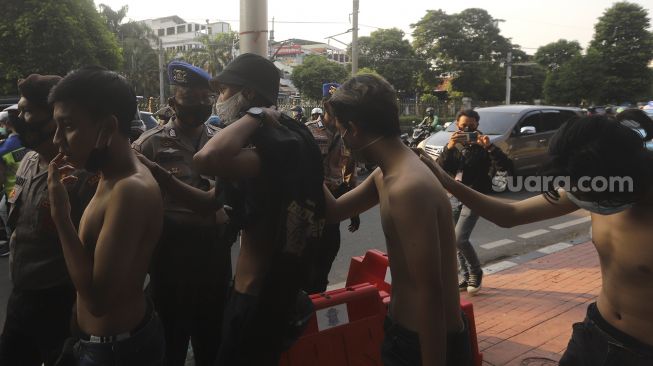 Aparat kepolisian menangkap sejumlah massa yang terlibat bentrokan di sekitar Gedung DPR RI, Jakarta, Rabu (7/10/2020). [Suara.com/Angga Budhiyanto]