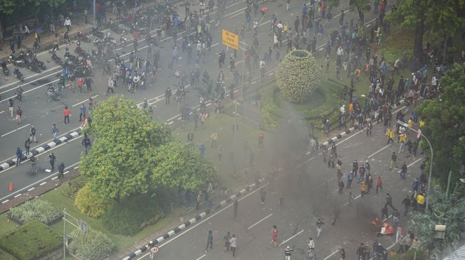 Pengunjuk rasa yang menolak pengesahan Undang-Undang Cipta Kerja berlarian saat polisi menghalau mereka di Jalan Medan Merdeka Selatan, Jakarta, Kamis (8/10/2020).   [ANTARA FOTO/Aditya Pradana Putra]