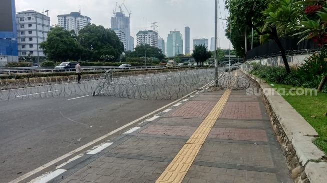 Ruas Jalan Gatot Subroto, tepatnya di depan gerbang utama Gedung DPR/MPR RI terpantau lengang, Kamis (8/10/2020). Jalan dari arah Polda Metro Jaya menuju 'gedung rakyat' tepat di sekitar fly over TVRI sudah ditutup kawat berduri. (Suara.com/Yosea Arga)