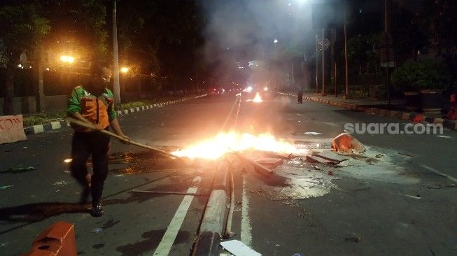 Petugas kebersihan berupaya membersihkan jalan dan memadamkan api di sekitar kawasan Patung Kuda,Jalan Medan Merdeka Barat, Jakarta Pusat, berangsur kondusif pasca kericuhan antara massa aksi tolak UU Cipta Kerja dan aparat gabungan, Kamis (8/10/2020). [Suara.com/Muhamad Yasir]