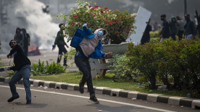 Pengunjuk rasa yang menolak pengesahan Undang-Undang Cipta Kerja menaiki patung pahlawan MH. Thamrin di Jalan Medan Merdeka Selatan, Jakarta, Kamis (8/10/2020). [ANTARA FOTO/Aditya Pradana Putra]