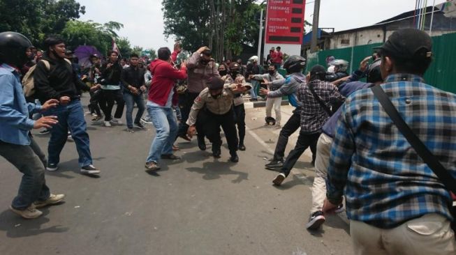 Anggota kepolisian berlari saat massa menerobos barikade di Jalan Daan Mogot, Jakarta Barat, Kamis (8/10).  [Suara.com/ Irfan Maulana]