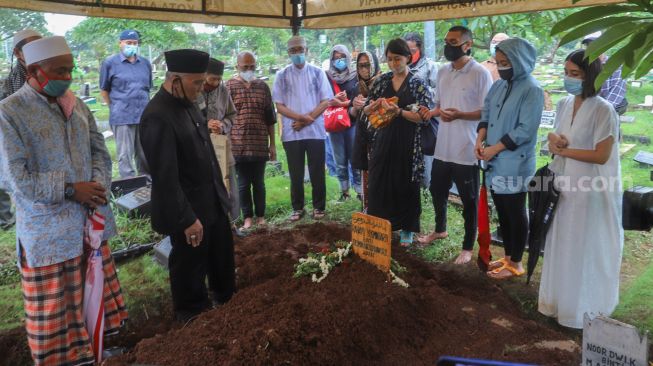 Musisi Rayi Putra Rahardja atau Rayi RAN dan keluarganya berdoa diatas pusara sang Ibunda di TPU Karet Bivak, Jakarta Pusat, Jumat (9/10). [Suara.com/Alfian Winanto]