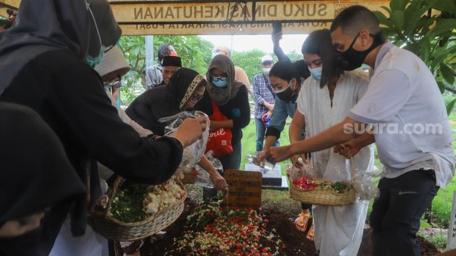 Musisi Rayi Putra Rahardja atau Rayi RAN dan keluarganya menabur bunga diatas pusara sang ibunda, Rahayu Joesmintarti di TPU Karet Bivak, Jakarta Pusat, Jumat (9/10). [Suara.com/Alfian Winanto]