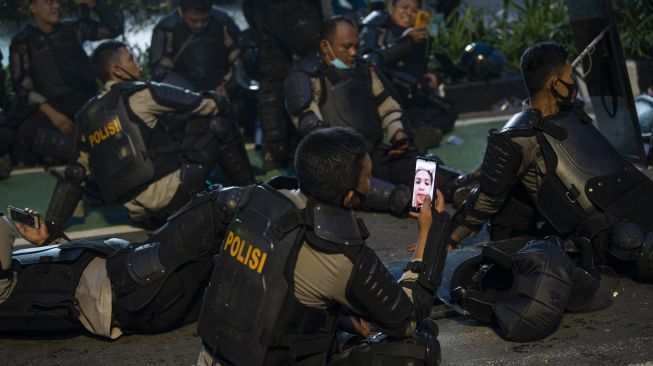 Polisi melakukan panggilan video dengan istrinya saat istirahat mengamankan unjuk rasa penolakan pengesahan Undang-Undang Cipta Kerja di Jalan MH. Thamrin, Jakarta, Kamis (8/10/2020).  [ANTARA FOTO/Aditya Pradana Putra]