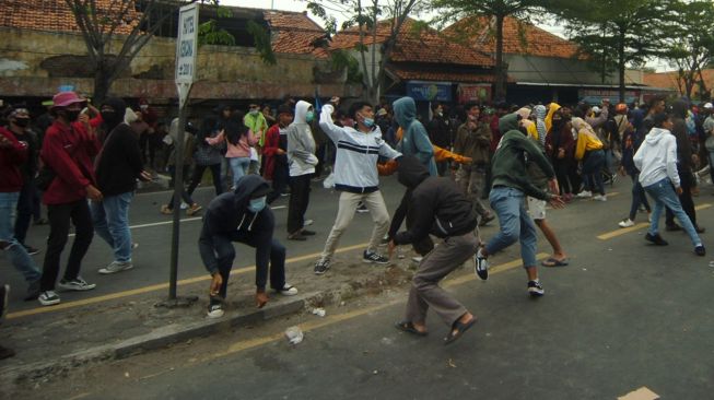 Massa melemparkan batu ke arah polisi saat unjuk rasa menolak Omnibus Law Undang Undang (UU) Cipta Kerja di Kantor DPRD Brebes, Jawa Tengah, Jumat (9/10/2020). [ANTARA FOTO/Oky Lukmansyah]