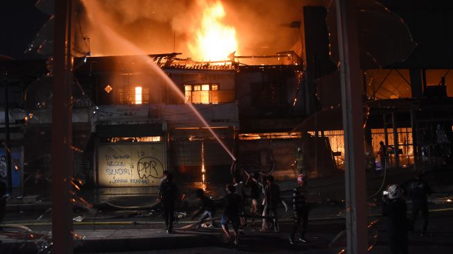 Petugas Pemadam Kebakaran dibantu warga memadamkan api yang menghanguskan bangunan bioskop Grand Theater di kawasan Senen, Jakarta, Kamis (8/10/2020) malam.  [ANTARA FOTO/Indrianto Eko Suwarso]