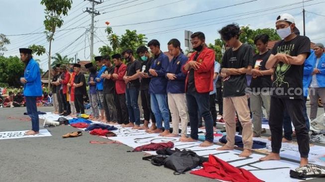 Massa aksi tolak UU Cipta Kerja melakukan salat Jumat di jalan raya depan Gedung DPRD Bantul, Jumat (9/10/2020). - (SuaraJogja.id/Hiskia Andika)