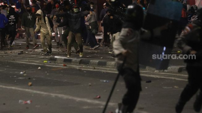 Polisi lari saat terjadi bentrokan dengan massa demonstran yang menolak disahkannya Undang-Undang Omnibus Law di Kawasan Tugu Tani, Jakarta Pusat, Kamis (8/10). [Suara.com/Alfian Winanto]