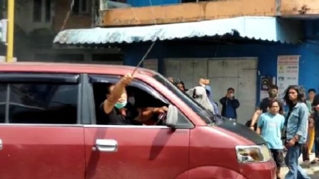 Seorang pengendara mobil mengacungkan parang panjang ke arah pendemo di Kota Parepare marah karena jalan dihalangi. [Ist]