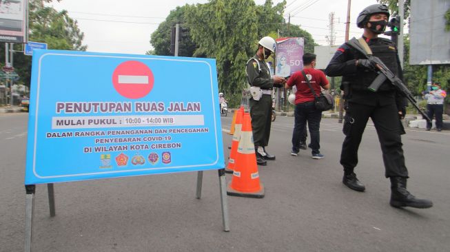 Petugas Dinas Perhubungan dan personel Brimob berjaga di ruas jalan Siliwangi, Kota Cirebon, Jawa Barat, Sabtu (10/10/2020). [ANTARA FOTO.Dedhez Anggara]