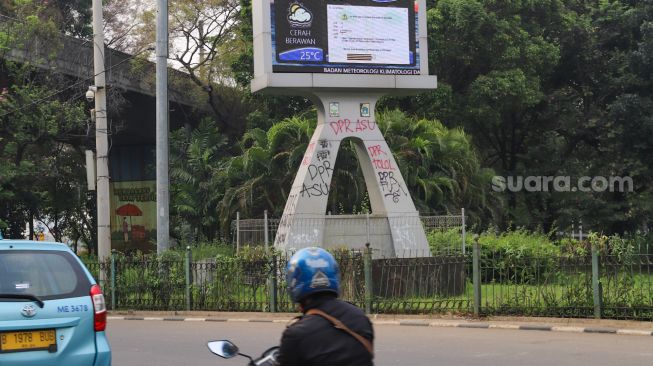 Coretan massa aksi demo tolak Omnibus Law Kamis (8/10) lalu di Tugu prakiraan cuaca yang masih belum dihapus di Jalan Merdeka Selatan, Jakarta Pusat, Sabtu (10/10). [Suara.com/Alfian Winanto]
