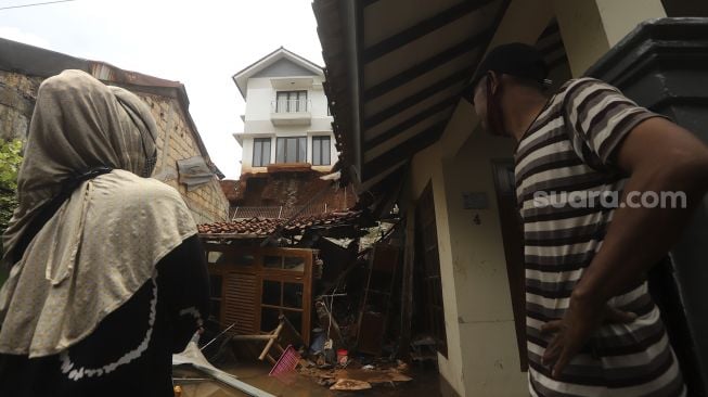 Warga mengamati salah satu rumah yang rusak berat akibat longsor di kawasan Ciganjur, Jagakarsa, Jakarta, Minggu (11/10/2020). [Suara.com/Angga Budhiyanto]