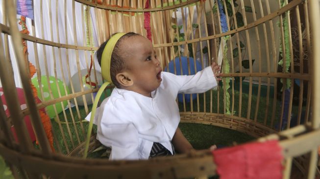 Seorang bayi dimasukkan ke dalam kurungan pada prosesi tradisi Tedak Siten di Kota Kediri, Jawa Timur, Minggu (11/10/2020). [ANTARA FOTO/Prasetia Fauzani