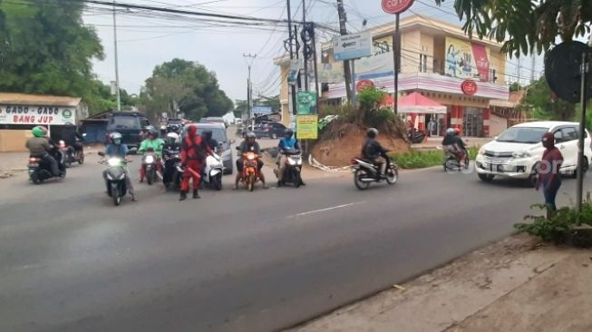 Dua juru parkir mengenakan kostum superhero Deadpool dan Spiderman saat tengah mengatur lalu lintas di  Simpang Tiga Mayabon, Cipocok Jaya, Kota Serang, Senin (12/10/2020). [Suara.com/Sofyan Hadi]