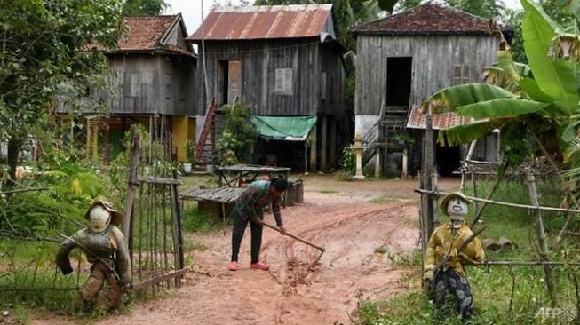 Tangkal Virus Corona, Warga Kamboja Pasang Orang-orangan Sawah di Depan Rumah. (AFP/Tang Chhin Sothy)