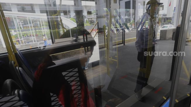 Seorang penumpang beraktivitas di dalam bus Transjakarta yang berhenti di Halte Transjakarta Bundaran HI, Jakarta, Senin (12/10/2020). [Suara.com/Angga Budhiyanto]