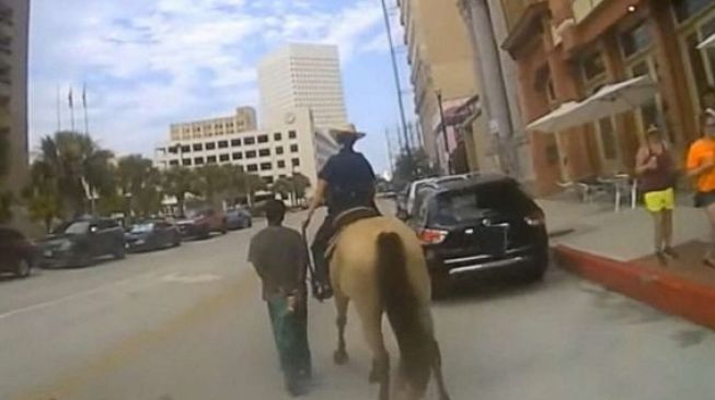 Seorang pria saat digiring oleh polisi berkuda dengan kondisi diikat dengan tali.[Galveston Police Dept]