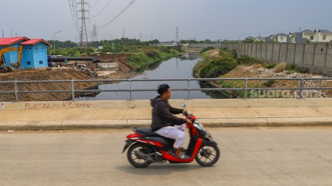 Pengendara motor melintas diatas aliran kali Blencong yang sudah bersih dari sampah di Desa Setia Asih, Kecamatan Tarumajaya, Kabupaten Bekasi, Jawa Barat, Selasa (13/10). [Suara.com/Alfian Winanto]