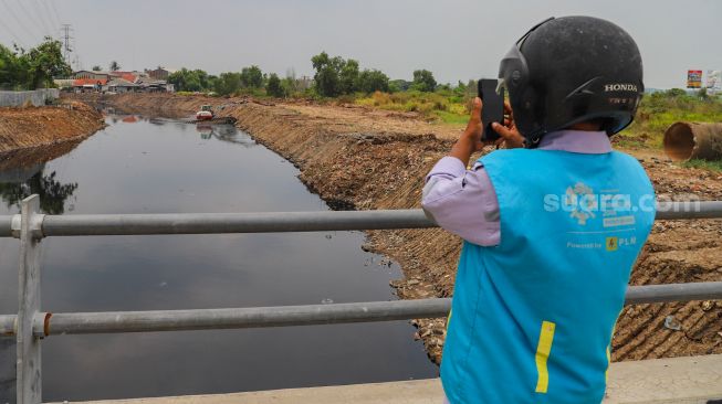 Watga sekitar melihat aliran kali Blencong yang sudah bersih dari sampah di Desa Setia Asih, Kecamatan Tarumajaya, Kabupaten Bekasi, Jawa Barat, Selasa (13/10). [Suara.com/Alfian Winanto]