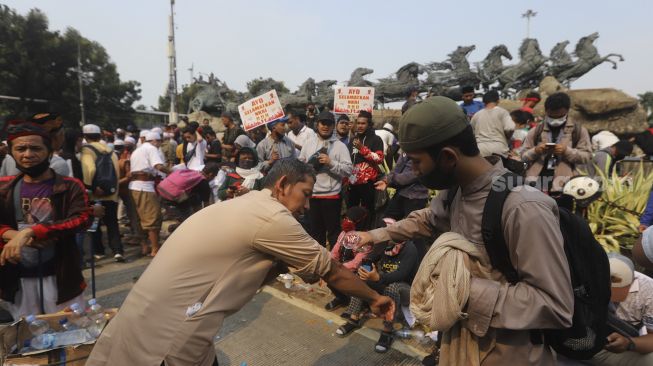 Sejumlah massa dari Persaudaraan Alumni (PA) 212 dan sejumlah ormas Islam berwudhu sebelum melaksanakan Shalat Ashar berjamaah disela-sela menggelar aksi unjuk rasa di kawasan Patung Kuda, Jakarta, Selasa (13/10/2020). [Suara.com/Angga Budhiyanto]