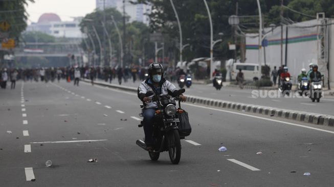 Pengendara sepeda motor berputar arah saat sejumlah massa terlibat bentrokan dengan aparat kepolisian saat aksi unjuk rasa tolak UU Cipta Kerja di depan Stasiun Gambir, Jakarta, Selasa (13/10/2020). [Suara.com/Angga Budhiyanto]