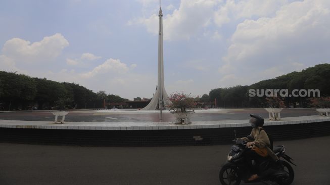 Pengunjung melintas di area Taman Mini Indonesia Indah (TMII), Jakarta, Rabu (14/10/2020). [Suara.com/Angga Budhiyanto]