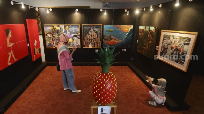 Pengunjung mengamati karya seni yang ditampilkan dalam pameran seni rupa bertajuk "Creative Freedom to Heal the Nation (Artists Response to the Pandemic)" di Perpustakaan Nasional, Jakarta, Kamis (15/10/2020). [Suara.com/Angga Budhiyanto]