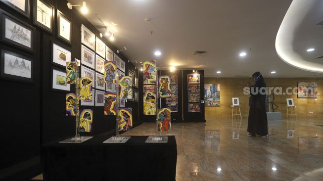 Pengunjung memotret karya seni yang ditampilkan dalam pameran seni rupa bertajuk "Creative Freedom to Heal the Nation (Artists Response to the Pandemic)" di Perpustakaan Nasional, Jakarta, Kamis (15/10/2020). [Suara.com/Angga Budhiyanto]