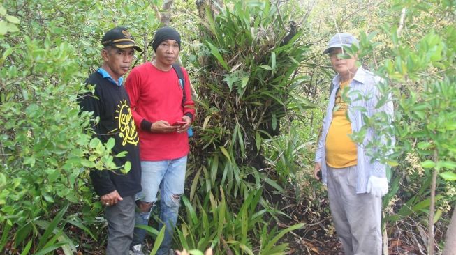 Sekretaris Kecamatan Kenohan, Kaspul (kanan) dan Kepala Desa Kahala, Mahlan (kanan) bersama seorang warga penunjuk jalan sedang berpose di depan rimbunnya anggrek hitam. (foto: Fatahillah Awwaluddin)