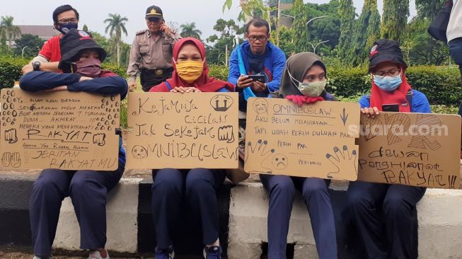 Buruh perempuan membawa poster kekecewaan terhadap pemerintah terkait UU Cipta Kerja, Jumat (16/10/2020). [Suara.com/Andi Ahmad Sulaendi]