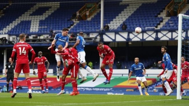 Pemain Everton Michael Keane menjebol gawang Liverpool dalam pertandingan Liga Premier Inggris di Goodison Park, Sabtu (17/10/2020). [AFP]