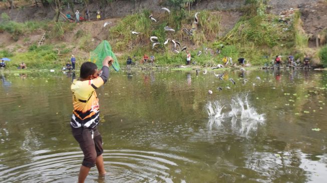 Petugas menebar ikan lele di Sungai Madiun, Kota Madiun, Jawa Timur, Minggu (18/10/2020).  [ANTARA FOTO/Siswowidodo]