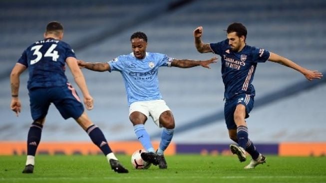 Pemain Manchester City Raheem Sterling dihadang dua pemain Arsenal dalam pertandingan Liga Premier Inggris yang berlangsung di Etihad Stadium, Sabtu (18/10/2020). [AFP]