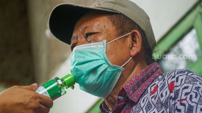 Bupati Banyumas mengoleskan minyak kayu putih pada masker yang dikenakan kepada komorbid saat pencanangan program Desa Jaga Komorbid di Desa Danaraja, Kecamatan/Kabupaten Banyumas, Senin (19/10/2020). (Suara.com/Anang Firmansyah)