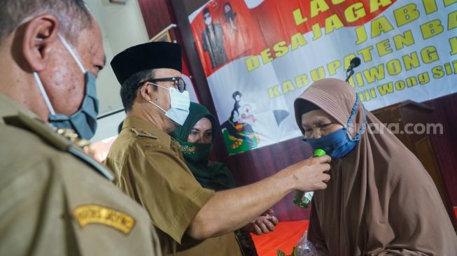 Bupati Banyumas mengoleskan minyak kayu putih pada masker yang dikenakan kepada komorbid saat pencanangan program Desa Jaga Komorbid di Desa Danaraja, Kecamatan/Kabupaten Banyumas, Senin (19/10/2020). (Suara.com/Anang Firmansyah)