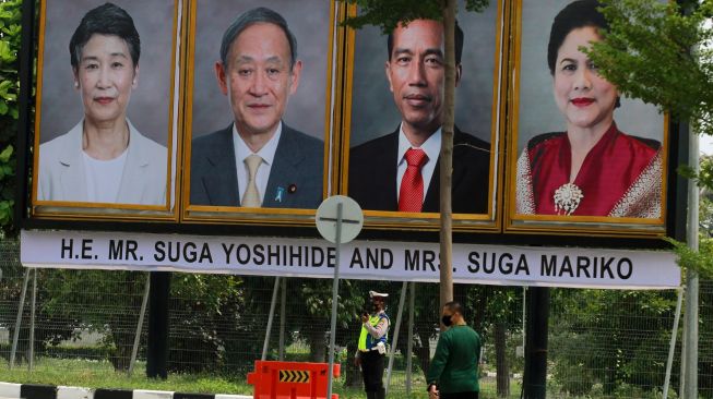 Petugas berjaga dekat foto Presiden Joko Widodo beserta Ibu Negara Iriana Joko Widodo dan Perdana Menteri Jepang Yoshihide Suga bersama Madam Suga Mariko di Bandara Soekarno Hatta, Tangerang, Banten, Selasa (20/10/2020). [ANTARA FOTO]
