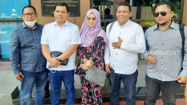 Okie Agustina (tengah) usai membuat perjanjian damai dengan travel umrah PT. Hidayatul Imam Abadi di Polres Metro Jakarta Pusat, Selasa (20/10). [Suara.com/Alfian Winanto]