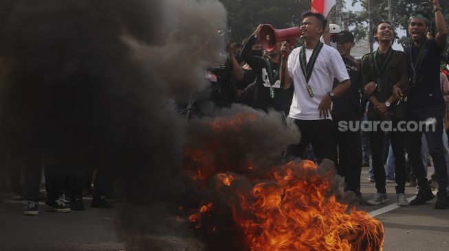 Mahasiswa yang tergabung dalam Himpunan Mahasiswa Islam (HMI) membakar ban saat melakukan aksi unjuk rasa di kawasan Patung Kuda, Jakarta, Selasa (20/10/2020). [Suara.com/Angga Budhiyanto]