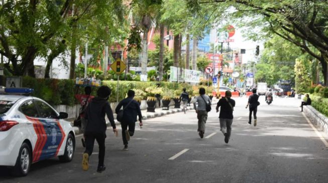 Polisi menangkap 2 remaja berpakaian serba hitam saat demo mahasiswa memperingati satu tahun Jokowi berkuasa di periode 2. (KanalKalimantan)